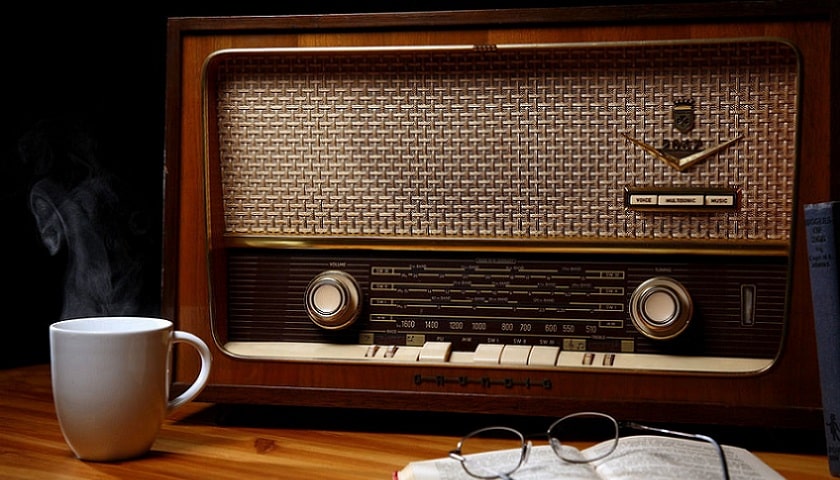 Rádio antigo, café e livro. Representando jingles antigos.